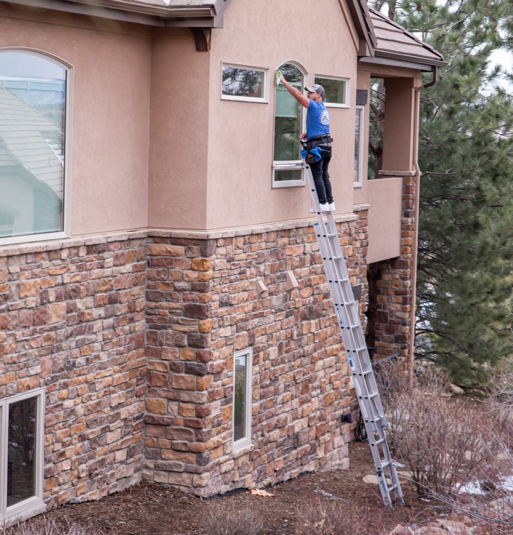 ClearCo tech cleaning windows on a ladder
